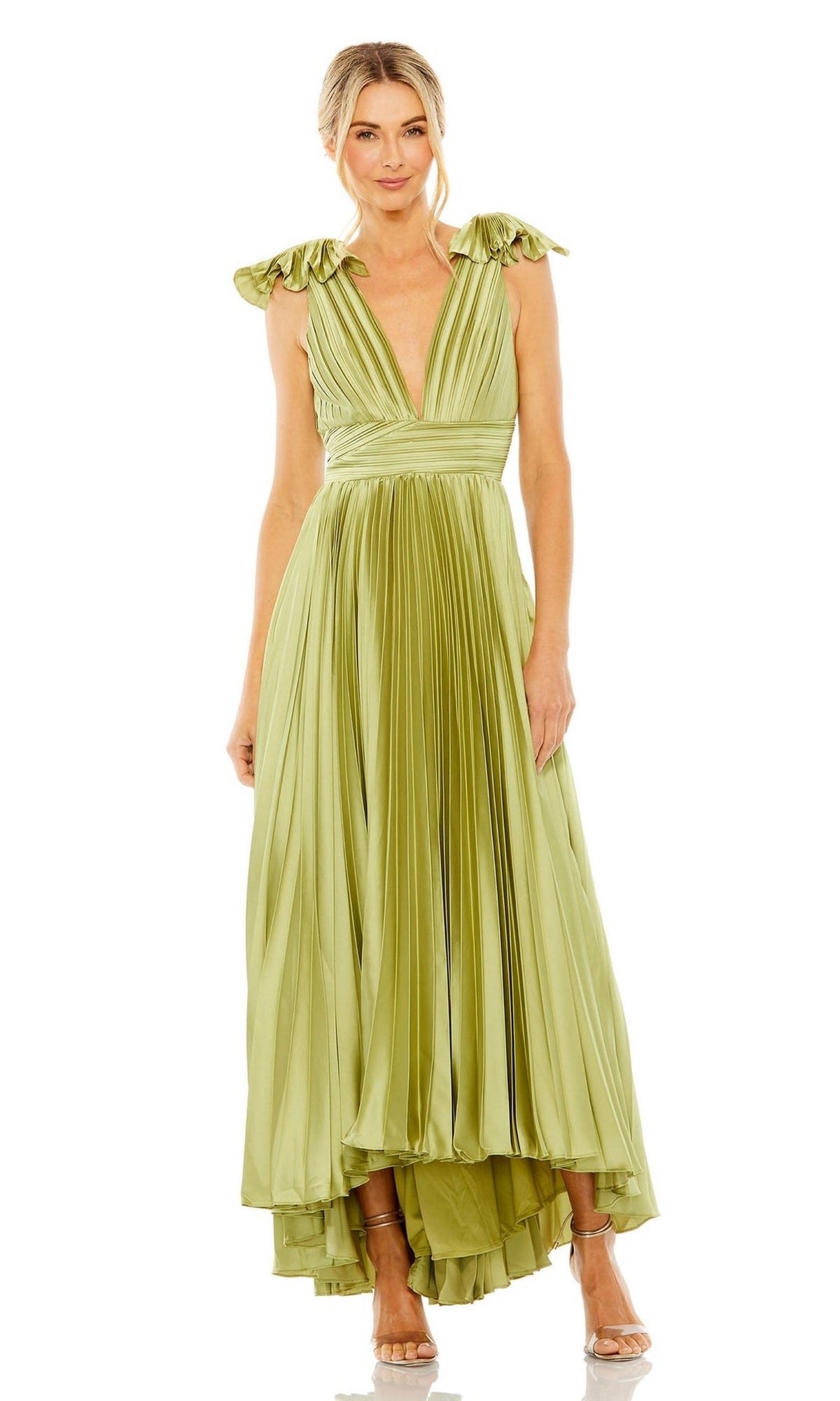 A woman wears the Mac Duggal 49734 pleated tea-length formal dress in light green, featuring a deep V-neckline and tied shoulder straps, paired with high-heeled sandals.